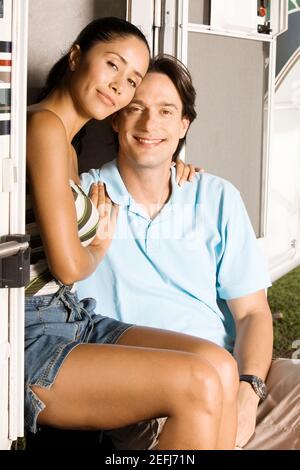 Porträt einer jungen Frau, die mit dem Arm um sich herum sitzt Ein mittelerwachsener Mann Stockfoto