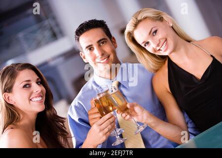 Porträt eines mittleren erwachsenen Mannes und zweier junger Frauen Toast anstoßen Stockfoto