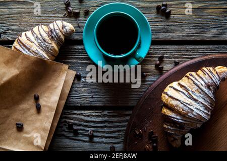 Croissant in einer Papiertüte mit einer Tasse Kaffee. Frühstück, Snack, Essen a Stockfoto