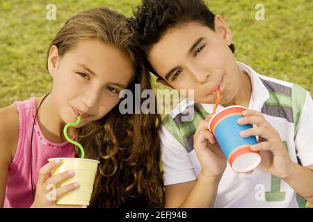 Porträt eines Bruders und einer Schwester, die mit Strohhalmen trinken Stockfoto