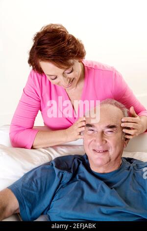 Aus der Perspektive einer älteren Frau, die einen älteren Mann gibt Mann eine Kopfmassage Stockfoto