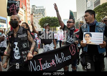 Ein Mitglied der Punks, der während einer Demonstration gegen den Militärputsch in der Innenstadt von Yangon den dreifingerigen Gruß mit einem Transparent hielt.das Militär von Myanmar nahm am 01. Februar die staatliche Beraterin von Myanmar Aung San Suu Kyi fest. 2021 und erklärte den Ausnahmezustand, während er die Macht im Land für ein Jahr nach dem Verlust der Wahl gegen die National League for Democracy (NLD) ergass. Stockfoto