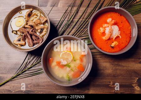 Satz serviert asiatische Suppen auf grauem Hintergrund der Ansicht von oben. Tom Yum Suppe, Aal Fischsuppe und Ramen Noodle Soup Stockfoto