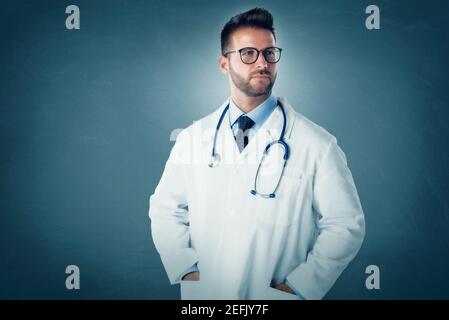 Studioportrait eines männlichen Arztes, der vor isoliertem Hintergrund steht und wegschaut. Stockfoto
