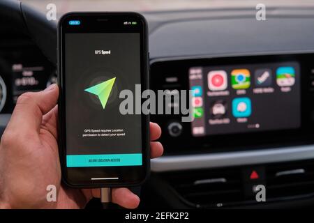 GPS-Geschwindigkeit Logo auf dem Bildschirm des Smartphones in mans Hand auf dem Hintergrund des Auto-Dashboard-Bildschirm mit der Anwendung von Navigation oder Karten. Januar Stockfoto