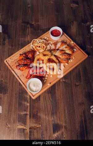 Große Auswahl an Snacks für Bier mit verschiedenen Soßen auf Pergament, Ansicht von oben Stockfoto