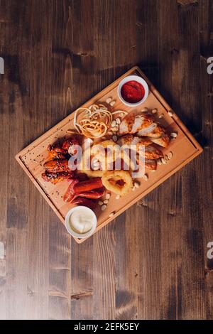 Große Auswahl an Snacks für Bier mit verschiedenen Soßen auf Pergament, Ansicht von oben Stockfoto