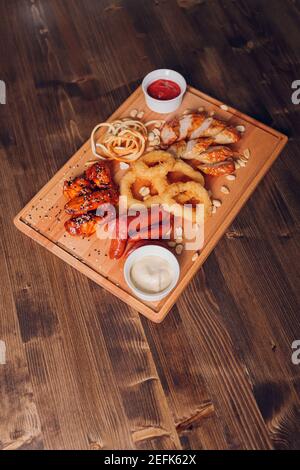 Große Auswahl an Snacks für Bier mit verschiedenen Soßen auf Pergament, Ansicht von oben Stockfoto