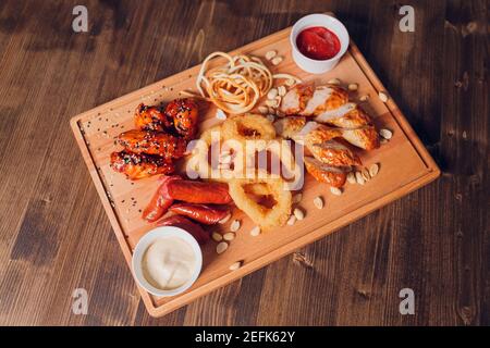 Große Auswahl an Snacks für Bier mit verschiedenen Soßen auf Pergament, Ansicht von oben Stockfoto