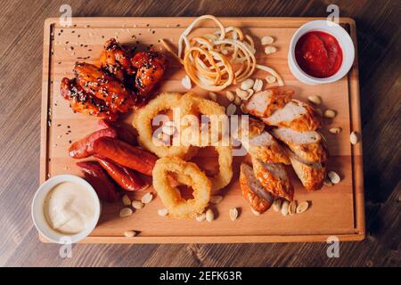 Große Auswahl an Snacks für Bier mit verschiedenen Soßen auf Pergament, Ansicht von oben Stockfoto