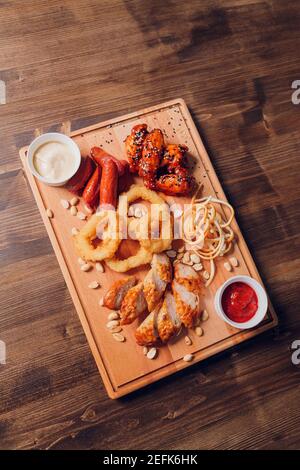 Große Auswahl an Snacks für Bier mit verschiedenen Soßen auf Pergament, Ansicht von oben Stockfoto