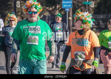 3-16-2019 Tulsa USA - Mann und Frau mittleren Alters Mit Federperücken und OCSO Teeshirts spazieren und plaudern St. Patricks Day Parade auf der Peoria Ave i Stockfoto