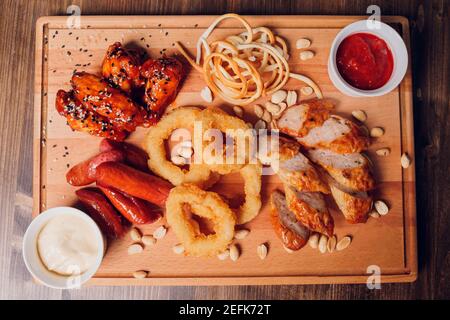 Große Auswahl an Snacks für Bier mit verschiedenen Soßen auf Pergament, Ansicht von oben Stockfoto