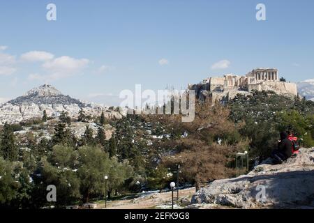 Athen, Griechenland - Februar 17 2021: Akropolis-Ansicht im Winter, mit Schnee in den Bergen. Mount Lycabettus im Hintergrund Stockfoto