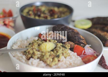 Kerala Mahlzeiten mit rotem Reis, Sardinen Curry, Sardinen braten und Kokosnuss-basierte grüne Gramm Curry. Alles im traditionellen kerala-Stil zubereitet Stockfoto