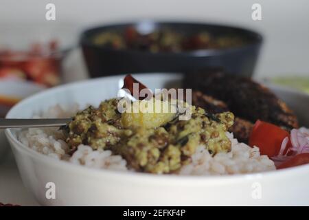 Kerala Mahlzeiten mit rotem Reis, Sardinen Curry, Sardinen braten und Kokosnuss-basierte grüne Gramm Curry. Alles im traditionellen kerala-Stil zubereitet Stockfoto