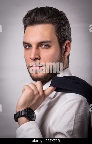 Weiße Geschäftsmann posiert in einem eleganten weißen Hemd gekleidet und Lehnt einen schwarzen Anzug auf seine Schulter Stockfoto