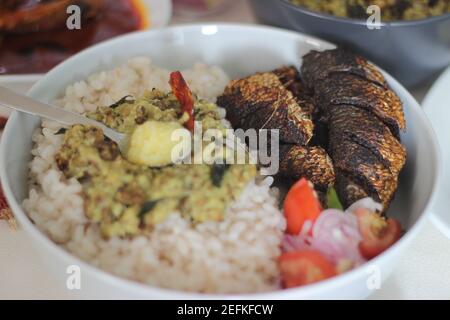 Kerala Mahlzeiten mit rotem Reis, Sardinen Curry, Sardinen braten und Kokosnuss-basierte grüne Gramm Curry. Alles im traditionellen kerala-Stil zubereitet Stockfoto