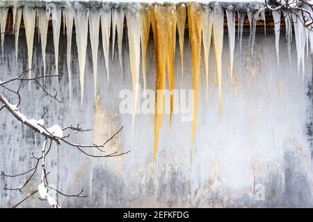 Eiszapfen, die vom Dach an den grauen Wal hängen Stockfoto