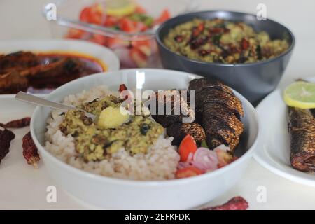 Kerala Mahlzeiten mit rotem Reis, Sardinen Curry, Sardinen braten und Kokosnuss-basierte grüne Gramm Curry. Alles im traditionellen kerala-Stil zubereitet Stockfoto