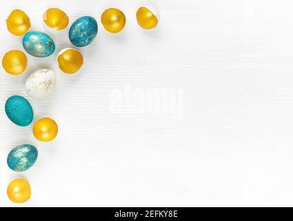 Osterhintergrund mit bunten handbemalten Eiern und goldenen Eierschalen auf weißem Holzhintergrund mit Kopierraum. Ostern Werbebanner mit Türkis Stockfoto