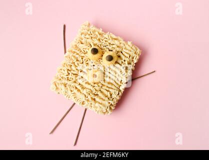 Kreative lustige Instant Nudeln auf rosa Hintergrund Stockfoto