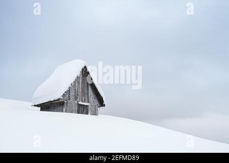 Winter verschneite Landschaft mit hölzernen schneebedeckten Hütte auf einem Hügel Stockfoto