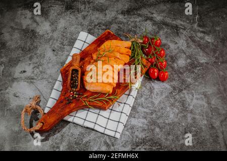 Rohes mariniertes Hühnerfleisch. Rohe Filetstücke.marinierte Hühnerfiletstücke in roter Marinade auf einer hölzernen Küchenbrettplatte mit Gewürzen. Stockfoto