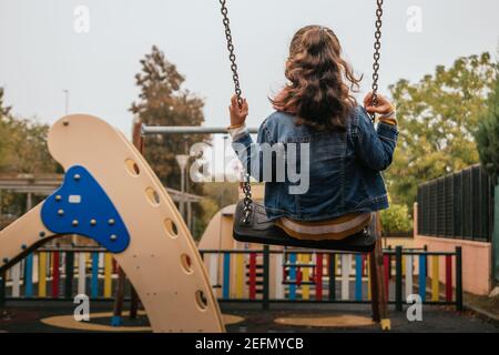 Mädchen schwingt auf einer Schaukel in einem öffentlichen Park Stockfoto