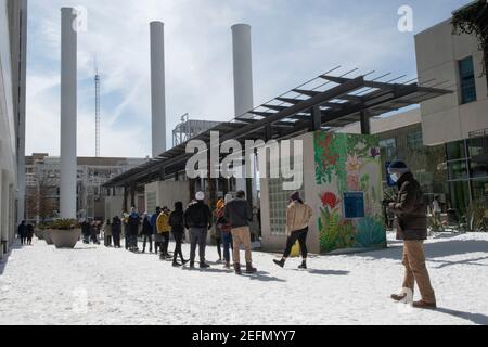 Austin, Texas, USA. Februar 2021, 16th. Die Bewohner von Austin, die in den Schnee gehen, stehen vor einem Händler Joe's Lebensmittelgeschäft im trendigen Seaholm District in der Innenstadt, während Texas sich von einem historischen Schneesturm und brutalen kalten Temperaturen kaum erholen kann. Die meisten Geschäfte werden die ganze Woche wegen des Sturms geschlossen. Quelle: Bob Daemmrich/ZUMA Wire/Alamy Live News Stockfoto