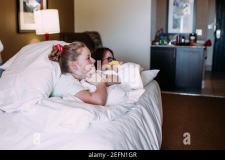 Zwei glückliche junge Mädchen entspannen auf einem Bett in einem Hotelzimmer Stockfoto