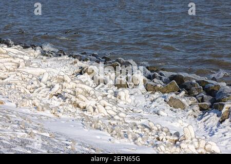 Holländischer Wellenbrecher mit Basaltsteinen, die im Winter mit Eis bedeckt sind Stockfoto