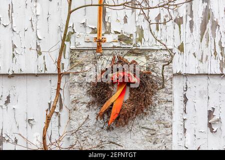 Alte Weihnachtskranz hängt an der Seite eines alten Heruntergekommenes Haus Stockfoto