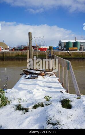 Ein schneebedeckter hölzerner Anlegesteg mit den Docks auf der gegenüberliegenden Seite des Flusses Haven in Boston Lincolnshire. Stockfoto