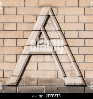 Großbuchstabe A in hellem Ziegel auf beigefarbener Klinkerwand Stockfoto