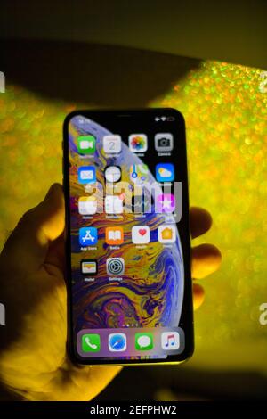 Paris, Frankreich - Oct 2, 2018: Defokussieren POV männliche Hand hält neue Apple Computers iPhone XS 11 12 13 pro neueste Modell vor einem goldenen Glitzer Hintergrund Stockfoto