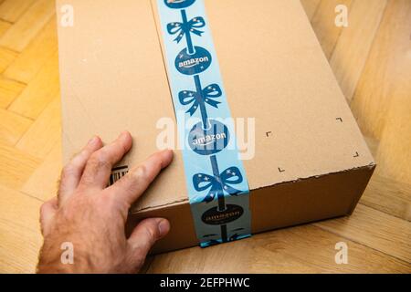 Paris, Frankreich - 16. Nov 2018: POV-Sicht persönliche Perspektive männliche Hand hält das neue Amazon Prime Papppaket mit Weihnachtslieferung Scotch Schutzband - Vorbereitung zum Auspacken Stockfoto