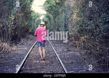 Blick Auf Den Mann, Der Auf Eisenbahnschienen Läuft.Blick Auf Den Mann, Der Am Eingang Des Tunnels Im Wald Steht. Stockfoto