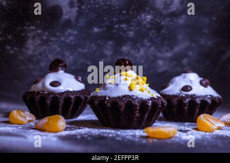 Schokoladen-Muffins bestreut mit Leckereien mit Kirschen und Schokolade und Kakao Stockfoto