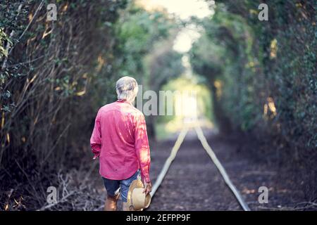 Blick Auf Den Mann, Der Auf Eisenbahnschienen Läuft.Blick Auf Den Mann, Der Am Eingang Des Tunnels Im Wald Steht. Stockfoto