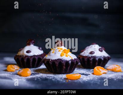 Schokoladen-Muffins bestreut mit Leckereien mit Kirschen und Schokolade und Kakao Stockfoto