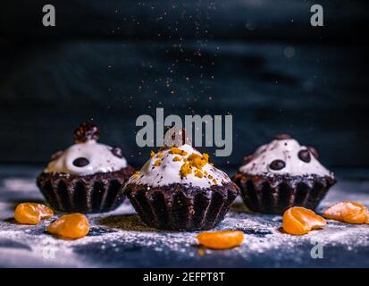 Schokoladen-Muffins bestreut mit Leckereien mit Kirschen und Schokolade und Kakao Stockfoto