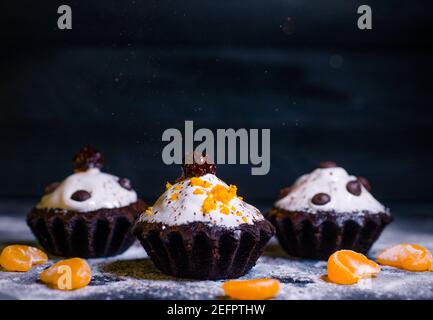 Schokoladen-Muffins bestreut mit Leckereien mit Kirschen und Schokolade und Kakao Stockfoto