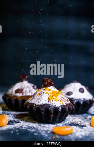 Schokoladen-Muffins bestreut mit Leckereien mit Kirschen und Schokolade und Kakao Stockfoto