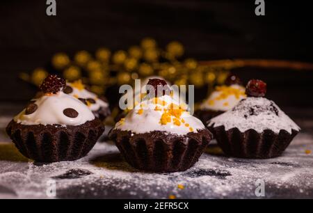 Schokoladen-Muffins bestreut mit Leckereien mit Kirschen und Schokolade und Kakao Stockfoto