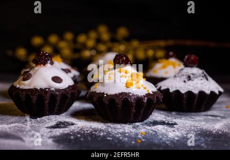 Schokoladen-Muffins bestreut mit Leckereien mit Kirschen und Schokolade und Kakao Stockfoto
