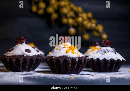 Schokoladen-Muffins bestreut mit Leckereien mit Kirschen und Schokolade und Kakao Stockfoto