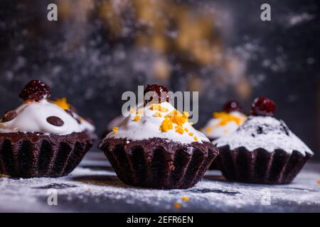Schokoladen-Muffins bestreut mit Leckereien mit Kirschen und Schokolade und Kakao Stockfoto