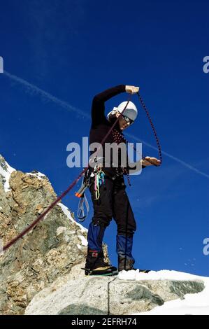 Ein Bergsteiger Wickelseil hoch auf einem Gipfel in der französische alpen Stockfoto