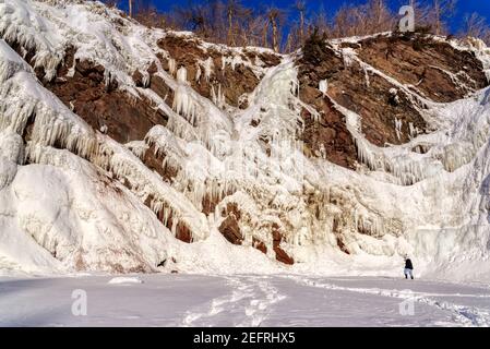 Ein Besucher, der an den Eiszapfen an den gefrorenen Rutschen de Chaudière in Charny bei Quebec City, Kanada, vorbeikommt Stockfoto